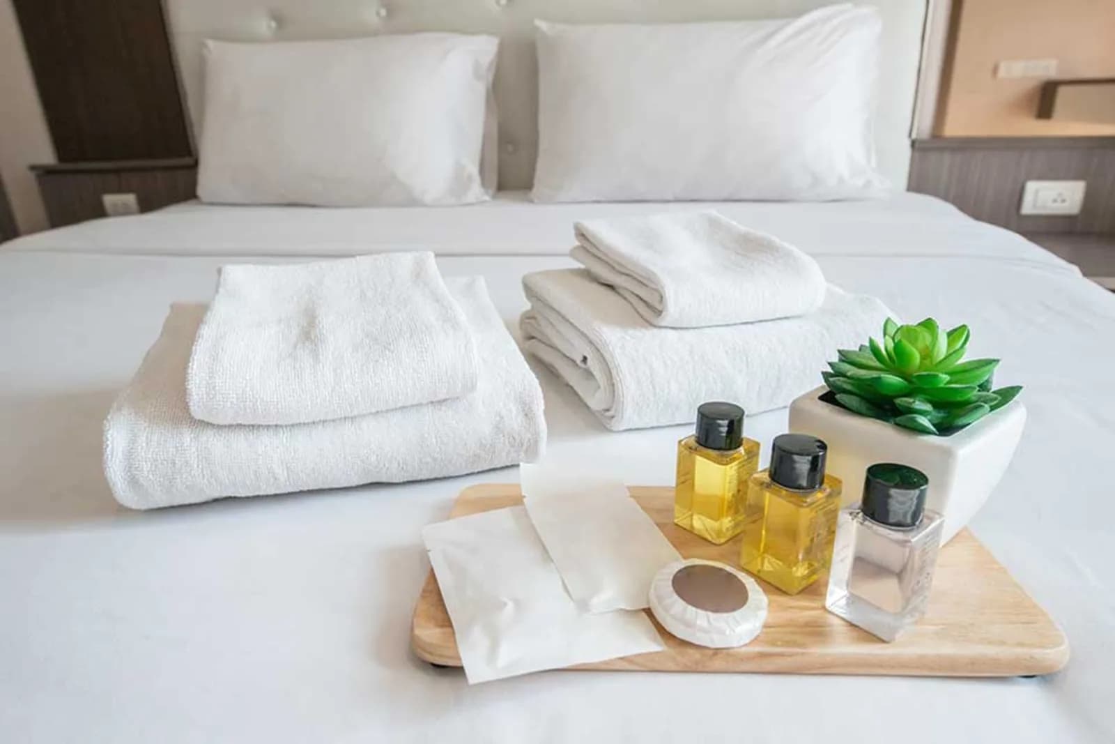 Hotel guest room amenities and towels laid out on a bed